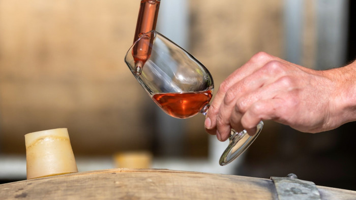 Close-up of an employee removing a sample of grape juice from an oak ageing barrel at a Chapel Down vineyard