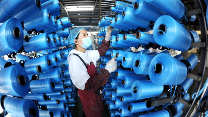 A worker changes reels in a woven bag factory