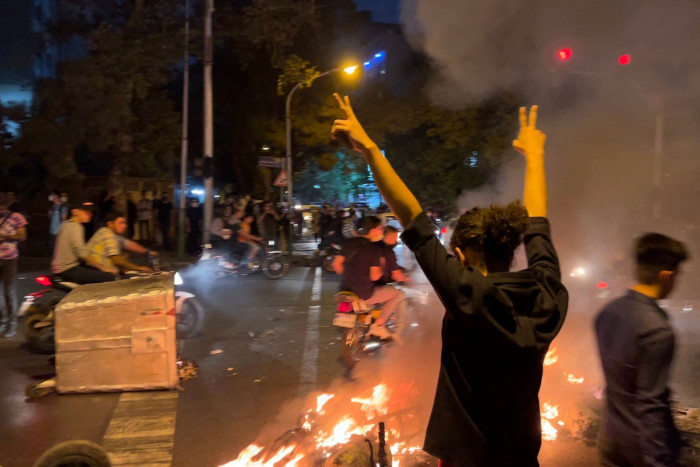 A demonstrator raises her arms and makes the victory sign during a protest