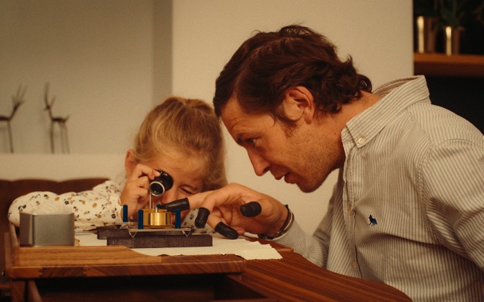 A man showing a girl the parts of a clock