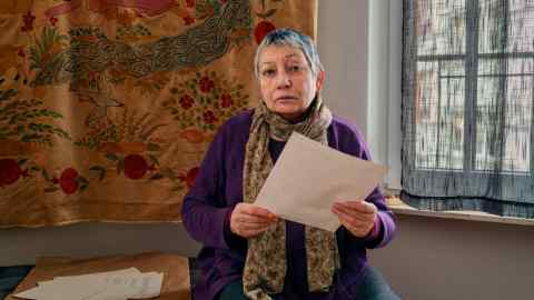 Writer Ludmila Ulitskaya, now 80 and with short grey hair, stands in her apartment holding pages of a manuscript