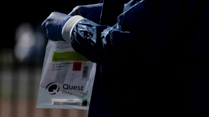 A healthcare worker holds a Quest Diagnostics bag containing a Covid-19 swab at a coronavirus drive-through testing site in Washington DC
