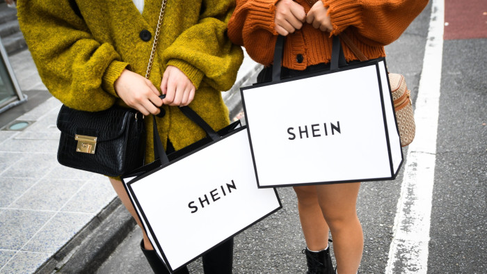Customers hold Shein shopping bags outside a Shein store in Tokyo, Japan