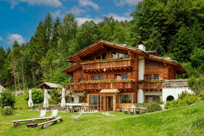 a large ski chalet made of woods. Behind is a lush green forest