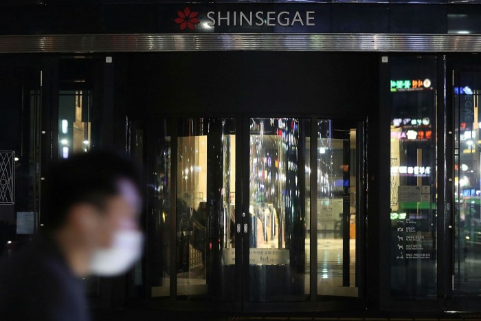 A masked person walks past the front doors of  Shinsegae Department Store’s Gangnam branch in southern Seoul