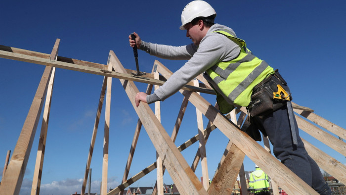 A construction worker builds a roof on an estate in Aylesbury, England
