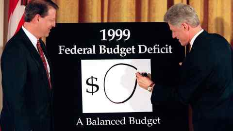 US Vice President Al Gore looks on as US President Bill Clinton places a “0” on the board showing what the federal deficit will be after unveiling his balanced budget plan for 1999