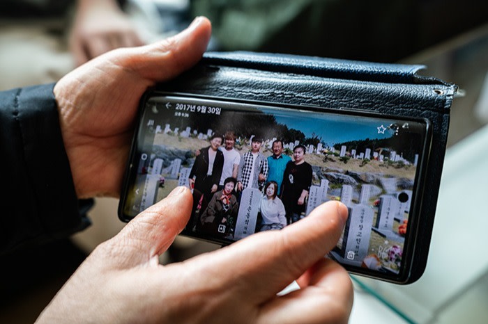 Son Myung-hwa shows a picture of her father’s final burial after his remains were returned to his family in South Korea