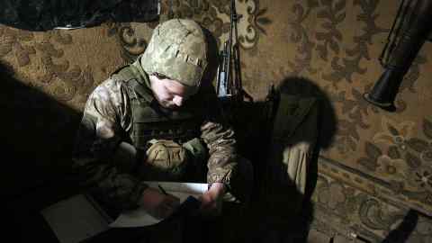 A Ukrainian serviceman writes notes at the front line in Donetsk last month