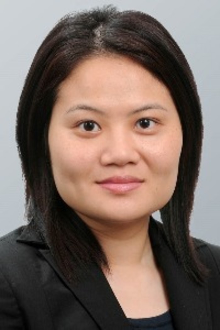An Asian woman in an office attire smiles with closed lips