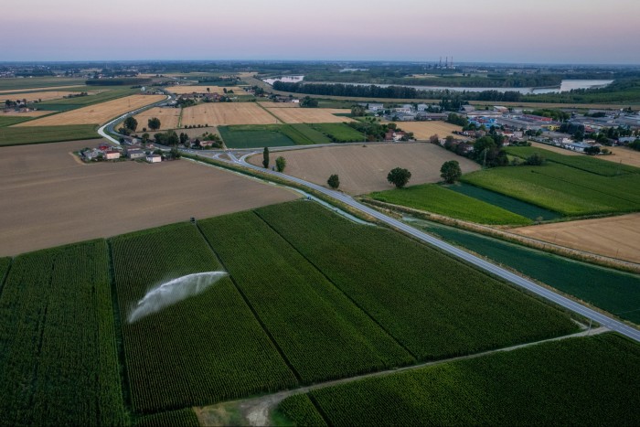 An aerial view of corn fields, with one being irrigated by a large sprinkler system