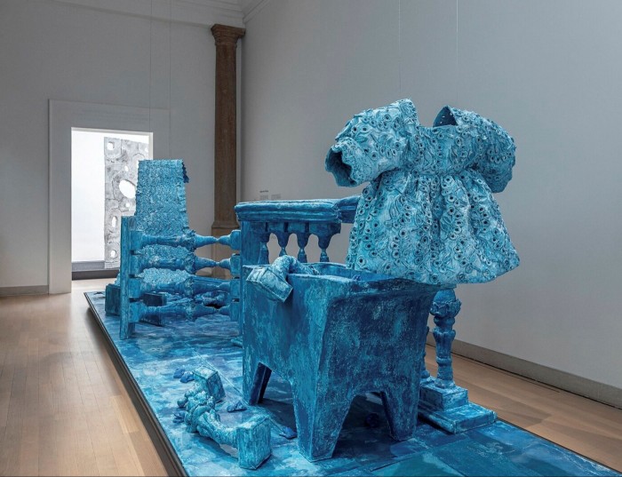 An artwork made from clothes and pieces of furniture, dyed bright blue  