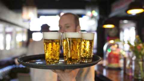 A barman carries a tray of draught Grolsch beer glasses, produced by SABMiller Plc, in a bar in Utrecht, Netherlands, on Sunday, May 1, 2016. Anheuser-Busch InBev NV accepted Asahi Group Holdings Ltd.'s offer to buy the Peroni, Grolsch and Meantime beer brands for 2.55 billion euros ($2.9 billion), clearing another hurdle in the European brewer's efforts to win regulatory approval for the purchase of SABMiller. Photographer: Jasper Juinen/Bloomberg