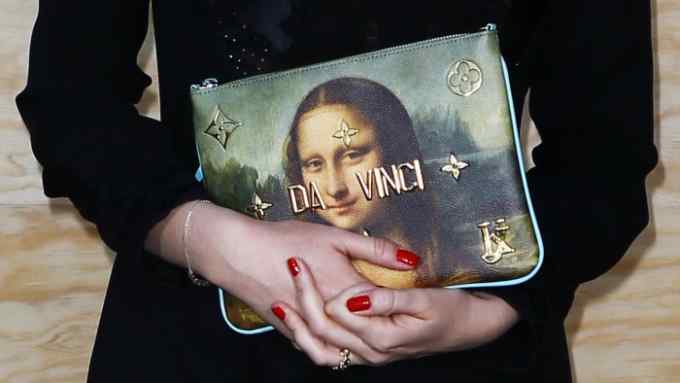 The hands of Director and executive Vice President of Louis Vuitton Delphine Arnault holds a bag during a photocall ahead of a diner for the launch of a Louis Vuitton leather goods collection in collaboration with US artist Jeff Koons, at the Louvre Museum in Paris, Tuesday, April 11, 2017. (AP Photo/Francois Mori)