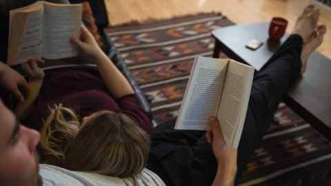 JB9XYR Couple reading books while relaxing in sofa in living room at home