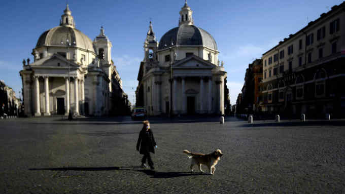 A woman takes her dog out in Piazza del Popolo on April 2, 2020 in Rome, during the country's lockdown aimed at curbing the spread of the COVID-19 infection, caused by the novel coronavirus. (Photo by Filippo MONTEFORTE / AFP) (Photo by FILIPPO MONTEFORTE/AFP via Getty Images)