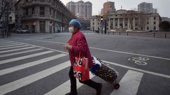 A person wearing a face mask walks across an empty intersection in Wuhan in central China's Hubei Province, Friday, Feb. 21, 2020. China's leadership sounded a cautious note Friday about the country's progress in halting the spread of the new virus that has now killed more than 2,200 people, after several days of upbeat messages. (Chinatopix via AP)
