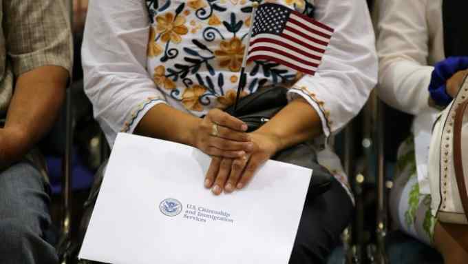 An attendee holds her new country's flag and her naturalization papers as she is sworn in during a U.S. citizenship ceremony in Los Angeles, U.S., July 18, 2017. Picture taken July 18, 2017. REUTERS/Mike Blake - RC1985AD4490