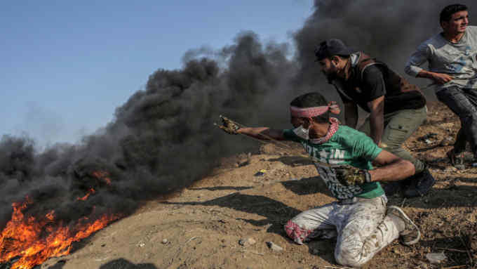 epa06741752 A Palestinian protester throws stones by his slingshot during clashes near the border with Israel in the east of Gaza Strip, 15 May 2018 (issued 16 May 2018). According to Palestinian medical sources, two Palestinian protesters were shot dead by the Israeli army on 15 May in Gaza, while thousands of Palestinians attended the funerals for some 25 of the 60 protesters killed a day earlier by the Israeli army during mass demonstrations. Palestinians are marking the Nakba Day, or the day of the disaster, when more than 700 thousand Palestinians were forcefully expelled from their villages during the war that led to the creation of the state of Israel on 15 May 1948. Protesters call for the right of Palestinians to return to their homeland.  EPA/MOHAMMED SABER