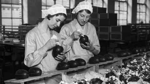 26th February 1932: Two women at the Cadbury's chocolate factory in Bournville, in the West Midlands join together chocolate Easter egg halves. (Photo by Fox Photos/Getty Images)