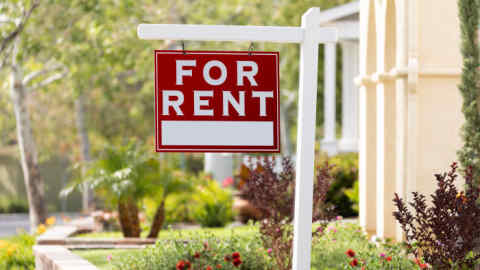 Red For Rent Real Estate Sign in Front House.