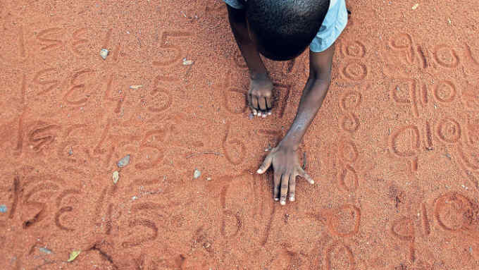 LIMPOPO, SOUTH AFRICA MARCH 18 (SOUTH AFRICA OUT): A grade 1 pupil practices mathematics in the sand during a lesson on March 18, 2016 in Limpopo, South Africa. Pupils and teachers at Mpepule primary school are forced to sleep in thier classrooms because there is no transport to take them to and from school. (Photo by Sandile Ndlovu/Sowetan/ Gallo Images /Getty Images)