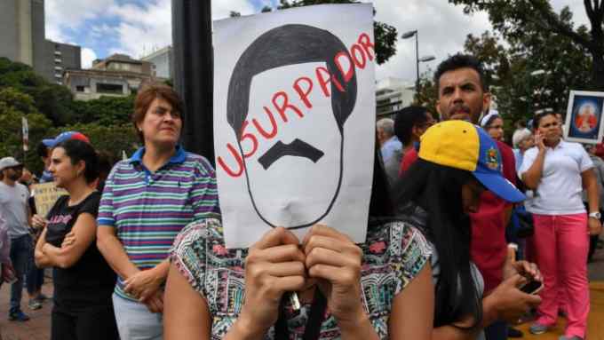 An opposition demonstrator holds a sign depicting the face contour of Venezuelan President Nicolas Maduro with a legend reading &quot;Usurper&quot;, during a protest against Maduro's government, called by opposition leader and self-proclaimed &quot;acting president&quot; Juan Guaido, at Altamira square in Caracas on January 30, 2019. - Venezuelan President Nicolas Maduro hit out Wednesday at military &quot;mercenaries&quot; he says are conspiring to divide the armed forces and plot a coup as the opposition planned a new protest to force the socialist leader from power. (Photo by Yuri CORTEZ / AFP) (Photo credit should read YURI CORTEZ/AFP/Getty Images)