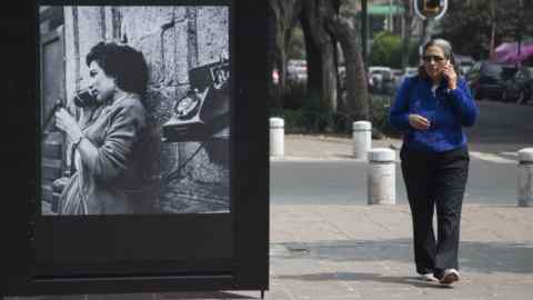 A woman talks on her phone as she walks next to a photo of the &quot;Roma Photo Exhibition&quot; on Alvaro Obregon Avenue, in Mexico City, Saturday, Feb. 9, 2019. As part of the activities organized in the framework of the Oscars ceremony and due to the nomination of the film ROMA by Mexican Director Alfonso Cuaron, Mexico City‚Äôs government inaugurated the &quot;Roma Photo Exhibit&quot; which are a series of photographs of the Roma neighborhood through time. (AP Photo/Christian Palma)