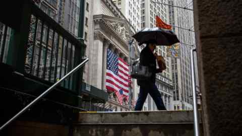 A pedestrian holds an umbrella while walking past the New York Stock Exchange (NYSE) in New York, U.S., on Monday, Nov. 13, 2017. U.S. stocks fluctuated, while Treasuries and the dollar edged higher as investors awaited clues on the direction of monetary policy and tax reform. Photographer: Michael Nagle/Bloomberg