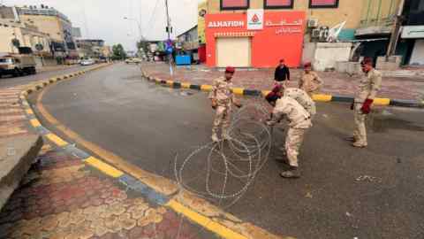 Soldiers place barbed wire on a street during a curfew imposed to prevent the spread of coronavirus disease (COVID-19), in Baghdad, Iraq March 18, 2020. REUTERS/Thaier Al-Sudani - RC2CMF9C3HBV