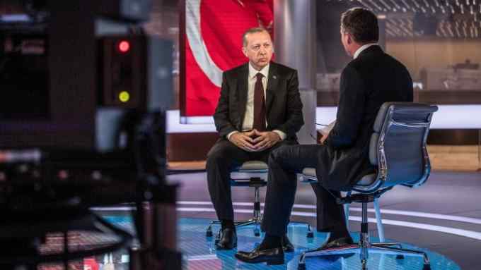Recep Tayyip Erdogan, Turkey's president, left, pauses as Guy Johnson, anchor for Bloomberg Television, speaks during a Bloomberg Television interview in London, U.K., on Monday, May 14, 2018. Erdogan said he intends to tighten his grip on the economy and take more responsibility for monetary policy if he wins an election next month. Photographer: Simon Dawson/Bloomberg
