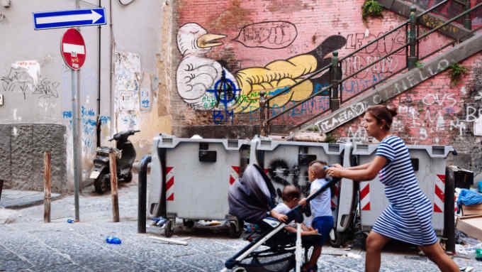HISTORIC CITY CENTRE, NAPLES, CAMPANIA, ITALY - 2017/08/10: Young woman pushing baby stroller while walking down a typical decadent street. (Photo by Raquel Maria Carbonell Pagola/LightRocket via Getty Images)