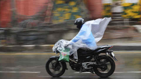 A Kashmiri man drives his motorbike covering himself with a plastic sheet as it rains in Srinagar, Indian controlled Kashmir, Tuesday, March 24, 2020. (AP Photo/Mukhtar Khan)