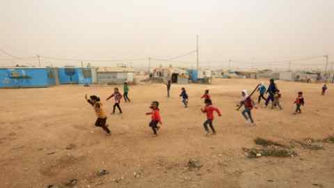epa06326962 Syrian refugee children play in a dusty wind day, on the inauguration day of the largest ever built solar plant in a refugee camp in the world, at Zaatari refugee camp, Jordan, 13 November 2017. The 12.9 megawatts plant was funded by the Government of Germany through the KfW Development Bank. The 15 million Euros project is expected to allow the United Nations High Commissioner for Refugees (UNHCR) to bring affordable and sustainable energy to some 80,000 Syrian refugees and its host community. EPA-EFE/STRINGER