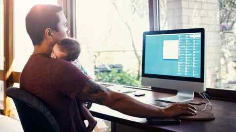 Shot of a young man working at home while holding his newborn baby son