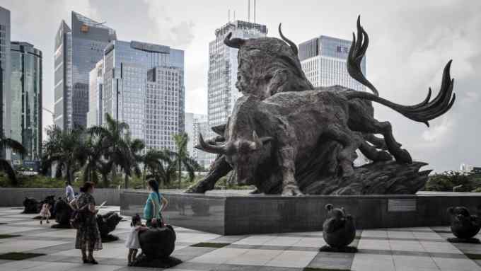 People stand in front of a sculpture of bulls at the entrance to the Shenzhen Stock Exchange building in Shenzhen, China, on Tuesday, Aug. 23, 2016. Derivative markets are pointing to renewed bets on yuan depreciation, with a three-month measure of expected price swings poised for the biggest monthly increase since January. Photographer: Qilai Shen/Bloomberg