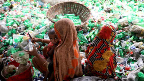 A woman with a child on her lap works at a plastic bottle recycling factory in Dhaka, Bangladesh, October 23, 2019. REUTERS/Mohammad Ponir Hossain