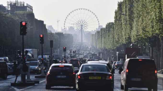TOPSHOT - Vehicles take the Champs Elysees avenue with the Concorde Plaza Ferris wheel in background, in Paris on April 21 ,2017, a day after a gunman opened fire on police on the avenue, killing a policeman and wounding two others in an attack claimed by the Islamic State group just days before the first round of the presidential election. / AFP PHOTO / Philippe LOPEZ (Photo credit should read PHILIPPE LOPEZ/AFP/Getty Images)