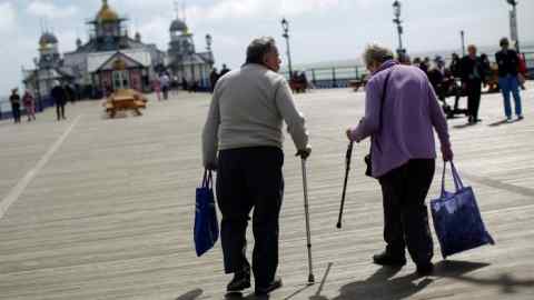 Elderly pedestrians walk using walking sticks on Eastbourne Pier in Eastbourne, U.K., on Monday, Aug. 22, 2016. Pensions are looking like an economic time bomb for Britain, meaning investors had better watch how the nation tries to defuse it. Photographer: Matthew Lloyd/Bloomberg