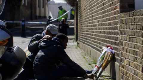 A man helps brother of the stabbing victim Israel Ogunsola at the scene where teenager Israel Ogunsola stabbed to death in Hackney, London on April 5, 2018.