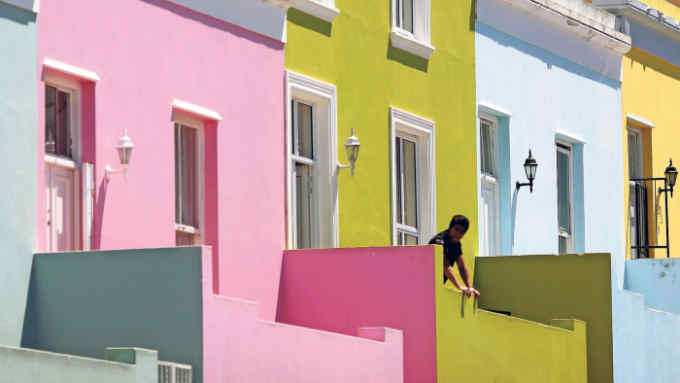 CAPE TOWN, SOUTH AFRICA - OCTOBER 20: A man relaxes outside his house in the Bo-Kaap area of Cape Town on October 20, 2009 in Cape Town, South Africa. The Bo-Kaap area is a predominantly Muslim area of Cape Town with brightly coloured painted houses that line many of the streets.. (Photo by Dan Kitwood/Getty Images)