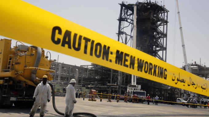 In this photo opportunity during a trip organized by Saudi information ministry, workers work in front of the recent attack Aramco's oil processing facility in Khurais, near Dammam in the Kingdom's Eastern Province, Friday, Sept. 20, 2019. (AP Photo/Amr Nabil)