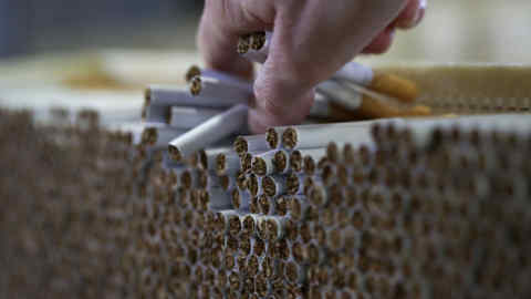 An employee checks cigarettes during production in the U.K. Photographer: Chris Ratcliffe/Bloomberg