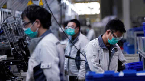 Employees wearing face masks work on a car seat assembly line at Yanfeng Adient factory in Shanghai, China, as the country is hit by an outbreak of a new coronavirus, February 24, 2020. REUTERS/Aly Song