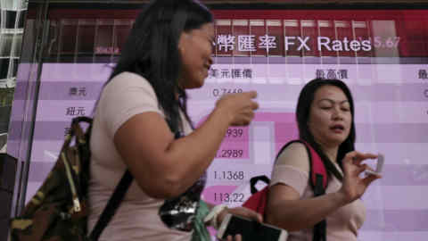 People walk past an electronic board showing the Hong Kong Stock Exchange index, Tuesday, July 4, 2017, in Hong Kong, China. Australian shares jumped Tuesday as investors awaited an interest rate decision by the central bank, while other Asian shares were mixed Tuesday ahead of a U.S. trading holiday. (AP Photo/Vincent Yu)