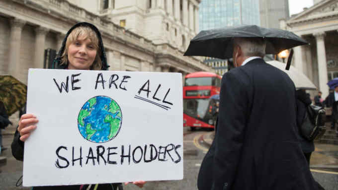 LONDON, ENGLAND - OCTOBER 14: An Extinction Rebellion protester holds up a placard saying &quot;We are all shareholders&quot; as they block the roads outside the Bank of England on October 14, 2019 in London, England. The protest targets the financial district for its investments in fossil fuels, part of an ongoing two week London protest targeting key Government locations in central London through non violent protests. (Photo by John Keeble/Getty Images)