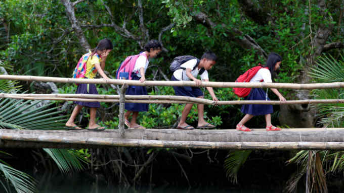 Schoolchildren, who walk six kilometers everyday to attend classes, cross a makeshift foot bridge in a village of Tagumpay in Pola, Oriental Mindoro, central Philippines March 1, 2017. REUTERS/Erik De Castro TPX IMAGES OF THE DAY - RC1BD7B6FCD0
