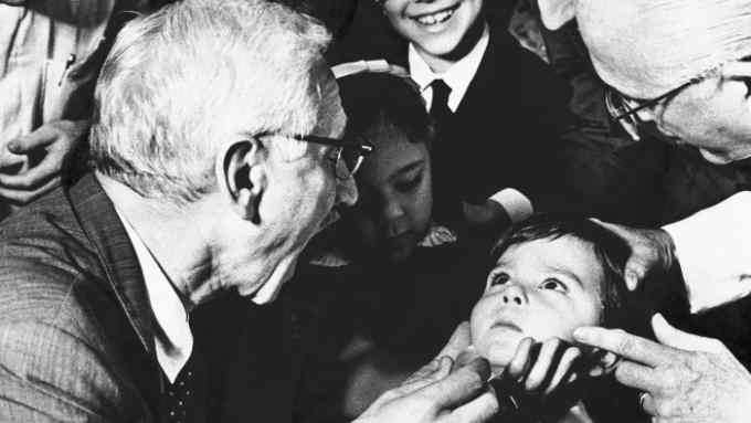 (Original Caption) Dr. Albert Sabin, who discovered a polio vaccine, asks five-year-old Luiz Inacio Gama to open wide please at the anti-polio Jesus hospital. Dr. Sabin and his wife, Jane, visited the institution and stopped in at a ward where children suffering from polio are treated.