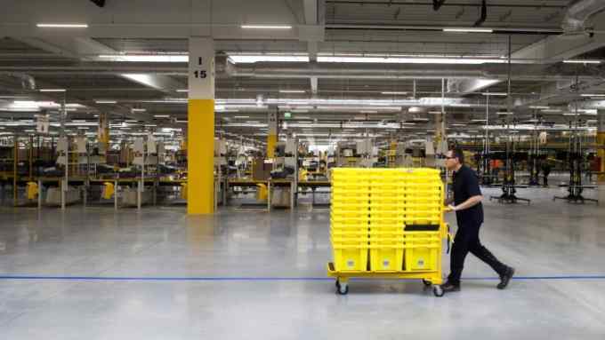 An employee pushes yellow product crates on a trolley across the work floor at the new Amazon Inc. fulfilment center on its official day of opening in Bielany Wroclawskie, Poland, on Tuesday, Oct. 28, 2014. The company announced on Monday that it's taking preorders for a streaming media stick that plugs into a TV, making it possible to watch a range of Internet video services. Photographer: Bartek Sadowski/Bloomberg