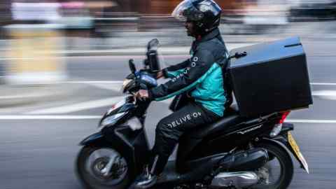 A Deliveroo, operated by Roofoods Ltd., food delivery driver rides his scooter on a street in London, U.K., on Monday, Aug. 22, 2016. The sizable amount of money going into the sector shows the cut-throat nature of the fast-moving food-delivery business. Photographer: Simon Dawson/Bloomberg